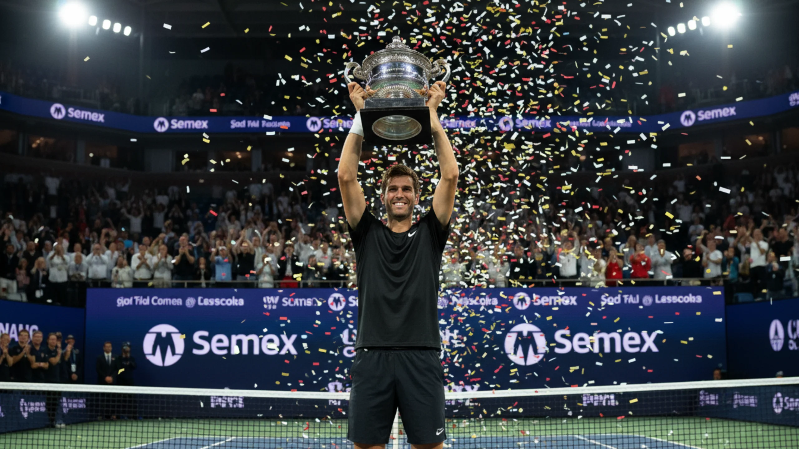 Tennisspieler hebt Pokal in die Hoehe auf dem Siegertreppchen bei grossem Turnier